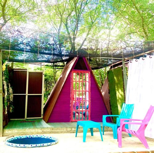 a small pink house with two chairs and a table at Finca turisrica bioaldea eywa todo un oasis in Neiva