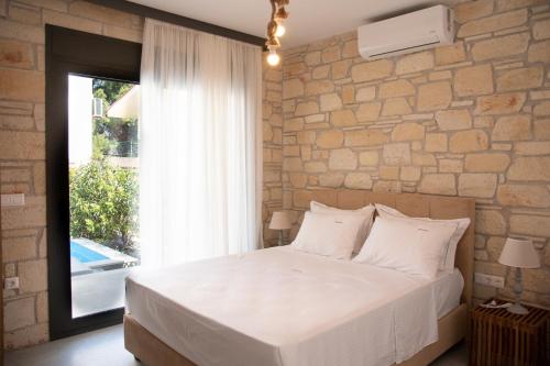 a bedroom with a large bed and a stone wall at Pietra Mare Villas in Polychrono