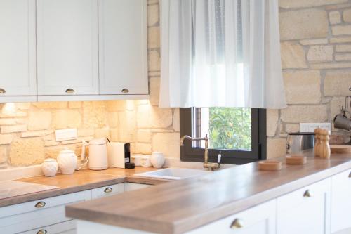 a kitchen with white cabinets and a sink and a window at Pietra Mare Villas in Polychrono