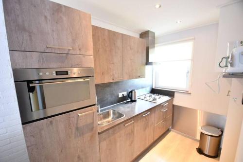 a kitchen with wooden cabinets and a stainless steel oven at Vrijvakantiehuis Houtenburgseweg 22 in Zoutelande