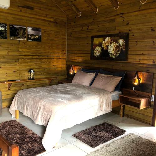a bedroom with a large bed with wooden walls at Pousada Village dos Canyons in Praia Grande