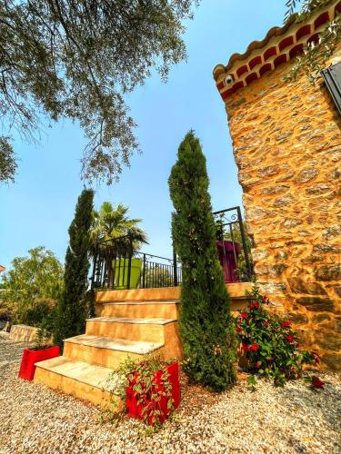 a stone building with stairs and flowers in a yard at Villa Napoléon Piscine&Jacuzzi in Le Somail