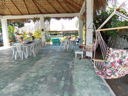 a patio with white chairs and tables and a hammock at Casa de Campo Nerys in SJM