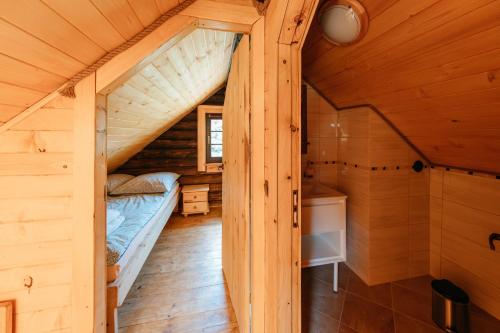 um quarto num chalé de madeira com uma cama e um lavatório em Bieszczadzka Bania em Lesko