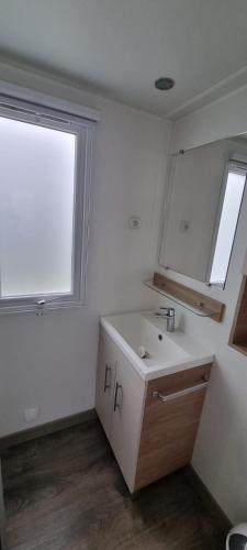 une salle de bain blanche avec un lavabo et une fenêtre dans l'établissement Mobil Home neuf tout confort dans un camping 4 étoiles, à Onzain