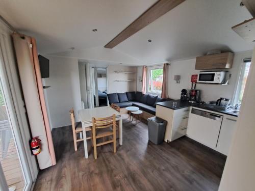 une cuisine et un salon avec une table et des chaises dans l'établissement Mobil Home neuf tout confort dans un camping 4 étoiles, à Onzain