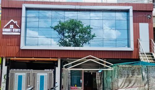 un edificio con un árbol delante de él en Smart Stays - MMMUT College - GKP Airport, en Gorakhpur