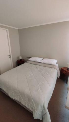 sypialnia z łóżkiem z białą pościelą i poduszkami w obiekcie Depa en Calama w mieście Calama