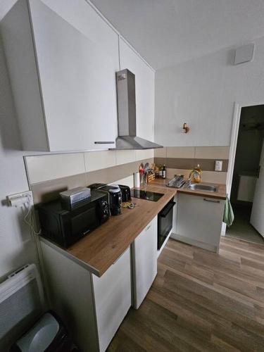 uma cozinha com armários brancos e um balcão de madeira em Le Verdun - centre Pau - calme em Pau