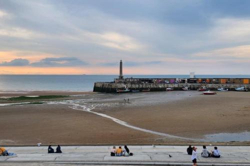 a group of people sitting on a sidewalk near the beach at Imperial Suites Heart Of Margate! sleeps 6 in Kent