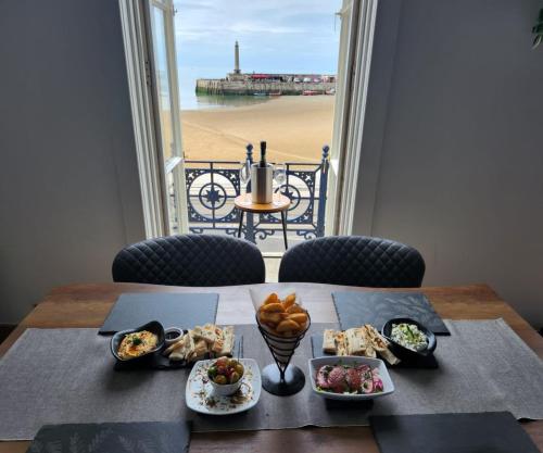 a table with plates of food and a view of the beach at Imperial Suites Heart Of Margate! sleeps 6 in Kent