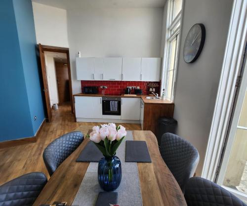 a dining room table with a vase of flowers on it at Imperial Suites Heart Of Margate! sleeps 6 in Kent