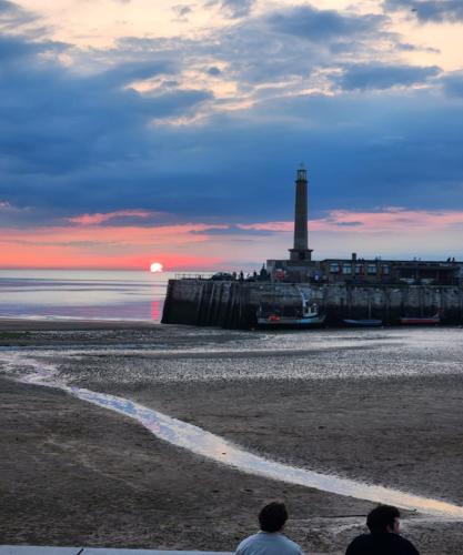 two people sitting on the beach with a lighthouse at Imperial Suites Heart Of Margate! sleeps 6 in Kent