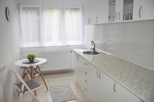 a white kitchen with a sink and a stool at Apartman DJURDJEVAK in Vršac