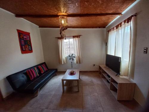 a living room with a couch and a tv at Casa Sutar Las Higueras in San Pedro de Atacama