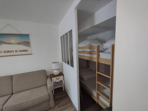 ein Wohnzimmer mit einem Sofa und einem Etagenbett in der Unterkunft Au charme de St Georges in Saint-Georges-de-Didonne