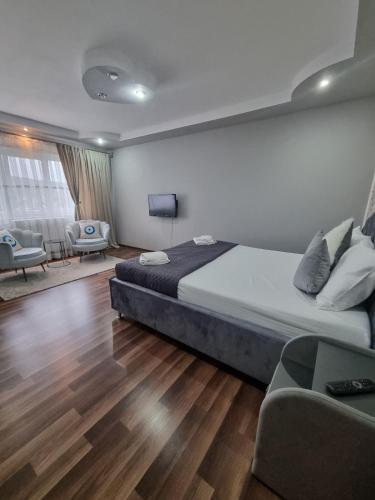 a bedroom with a bed and a living room with chairs at Emily Residence in Curtea de Argeş