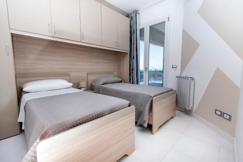 due letti in una piccola stanza con una finestra di Casa vacanza lido a Sciacca