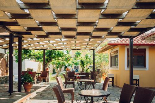 a patio with tables and chairs under a wooden pergola at Villa Yianna in Néa Meságkala