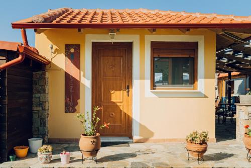 a small house with a wooden door and potted plants at Villa Yianna in Néa Meságkala