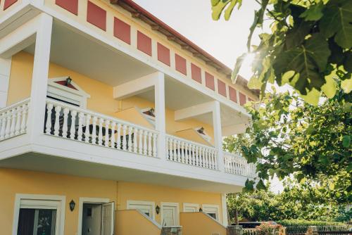 a yellow building with a white balcony at Villa Yianna in Néa Meságkala