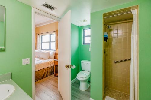 ein Badezimmer mit grünen Wänden, einem WC und einer Dusche in der Unterkunft All Seasons Vacation Resort by Libertè in St Pete Beach