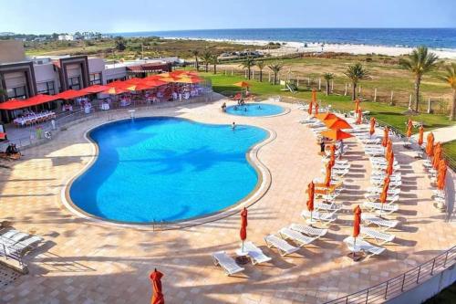 uma vista para uma piscina com cadeiras e guarda-sóis em Andalucia Bizerte plage et piscine em Bizerte