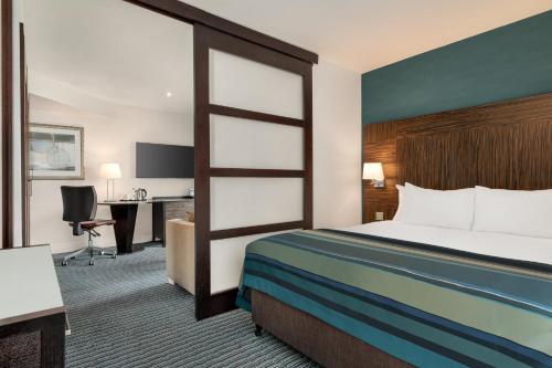 a hotel room with a bed and a desk at Holiday Inn Birmingham Airport - NEC by IHG in Bickenhill