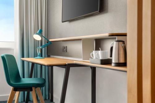 a desk with a green chair and a lamp at Holiday Inn Birmingham Airport - NEC by IHG in Bickenhill