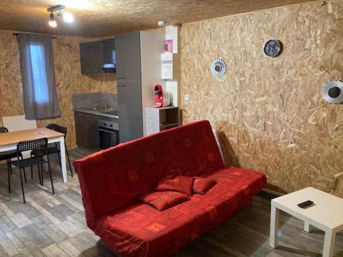 een rode bank in een woonkamer met een keuken bij Chalet climatisé n°2 in Verrières