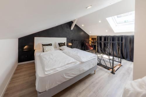 um quarto com uma cama grande e lençóis brancos em Le Vulcano : duplex lounge ! em Vesoul
