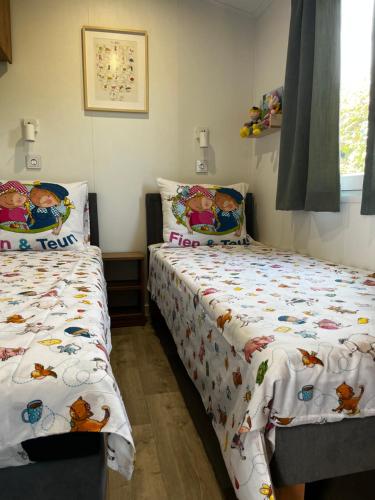 een slaapkamer met 2 aparte bedden naast een raam bij Chalet Boerenbries - Heerlijk chalet met overkapt terras en 2 slaapkamers - max 4 pers - 3 km van Noordzee - locatie op camping Moorhoek 5 in Rockanje