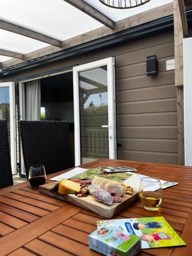 a table with a plate of food and a glass of wine at Chalet Boerenbries - Heerlijk chalet met overkapt terras en 2 slaapkamers - max 4 pers - 3 km van Noordzee - locatie op camping Moorhoek 5 in Rockanje