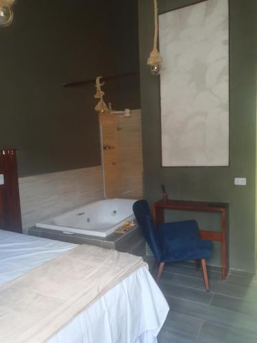 a bedroom with a tub and a bed and a chair at ALIZE CUMBUCO in Cumbuco