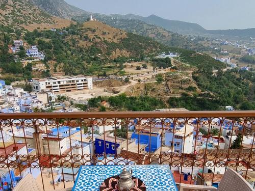 a table on a balcony with a view of a city at Casa Meftah Blue in Chefchaouene