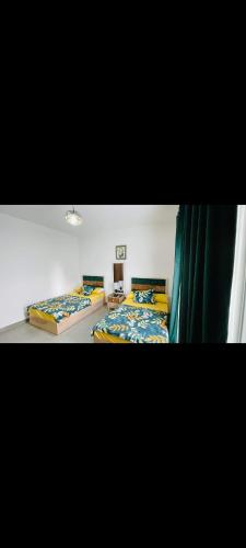 - 2 lits dans une chambre avec des rideaux verts dans l'établissement شاليه بقريه امواج سيدي عبد الرحمن, à El Alamein
