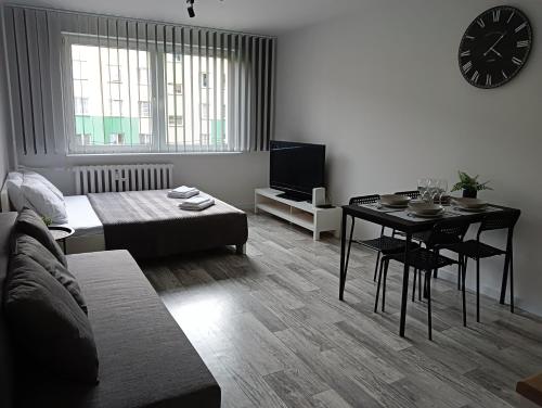 sala de estar con cama, mesa y reloj en Apartamenty Oświęcim klimatyzacja air-conditioned, en Oświęcim