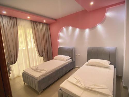 Duas camas num quarto com paredes cor-de-rosa em Chloe Apartament em Berati