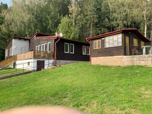 two houses on a grassy field with trees in the background at Chaty Dobrá Voda 86 in Horní Planá