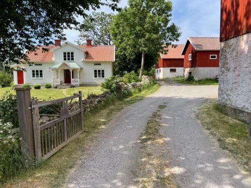 a dirt road in front of a house with a fence at Backgårdens Timmerstuga in Falköping