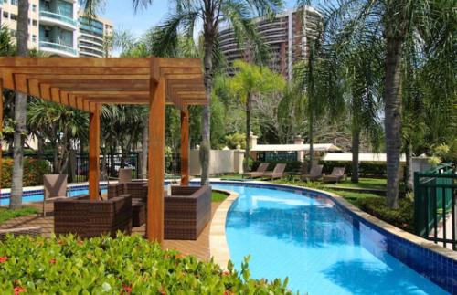 a swimming pool with a wooden gazebo next to a pool at Flat com Vista Panorâmica -15- na Barra da Tijuca - Estacionamento Gratuito - Frigobar - Ar condicionado - Piscina - Academia - Balsa para Praia Grátis - Varanda - Vista Parcial Mar e Lagoa in Barra da Tijuca