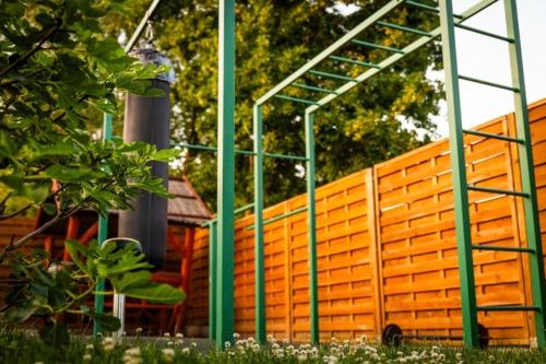 a wooden fence with green poles in the grass at Respect Apartament in Hévíz