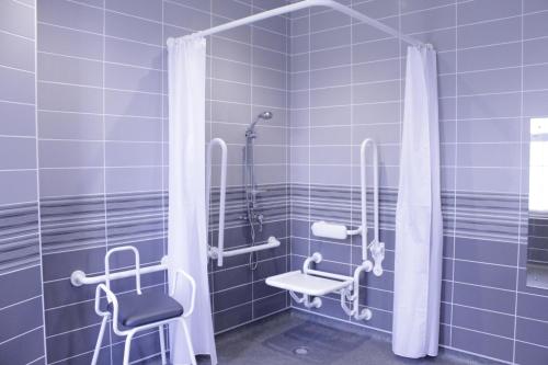 a blue tiled bathroom with a shower and a chair at Gwesty Seren Hotel in Blaenau-Ffestiniog
