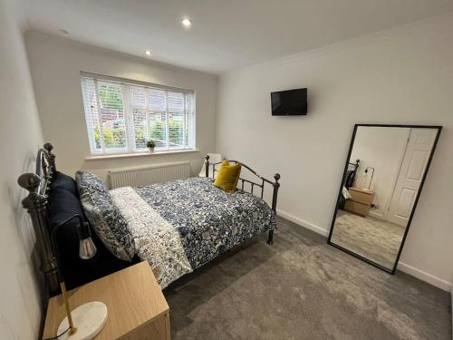 - une chambre avec un lit et un miroir dans l'établissement Idyllic bungalow, ideal location in West Lancashire, à Burscough