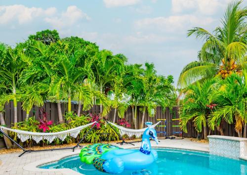 a pool at a resort with a mermaid on a raft at Colorful Home - Pool - Game Room - Basketball Court - BBQ & More in Fort Lauderdale