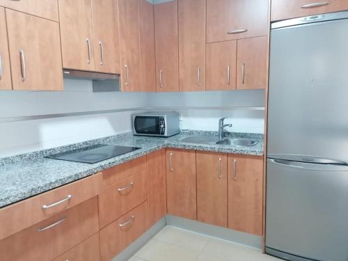 cocina con armarios de madera, fregadero y nevera en Apartamento Moya - Playa y Sol, en Aguadulce