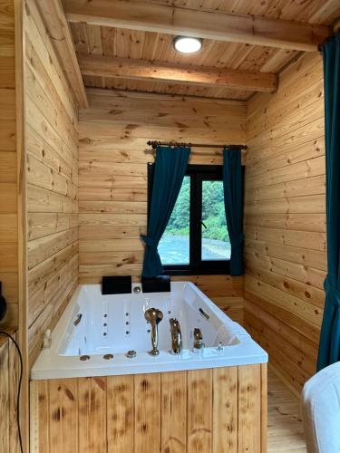 a bathroom with a tub in a wooden room at Kiana Bungalov in Ardeşen