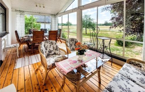 eine abgeschirmte Veranda mit einem Tisch und Stühlen in der Unterkunft Beautiful Home In Munka-ljungby With House A Panoramic View in Boarp