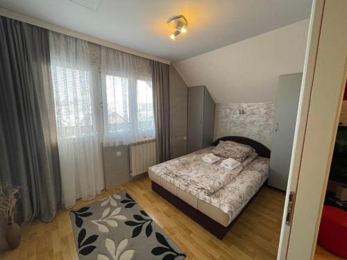 um pequeno quarto com uma cama e uma grande janela em APARTMANI JASMINA em Zlatibor