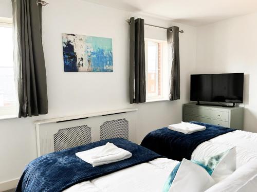 a bedroom with two beds and a tv on the wall at Turners Court in Melksham